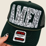 Hand holding Olive Green Amen Trucker Hat.