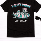 Flat lay photo of a black t-shirt with a skeleton in an inner tube with a juice box. 
